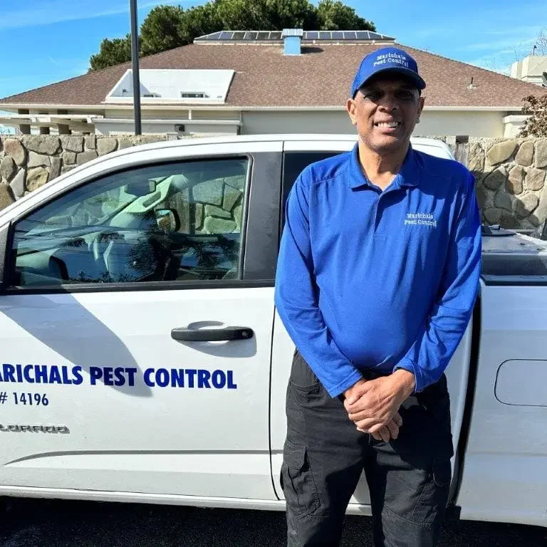 Marichal posing next to his pest control truck, prepared for pest management services.