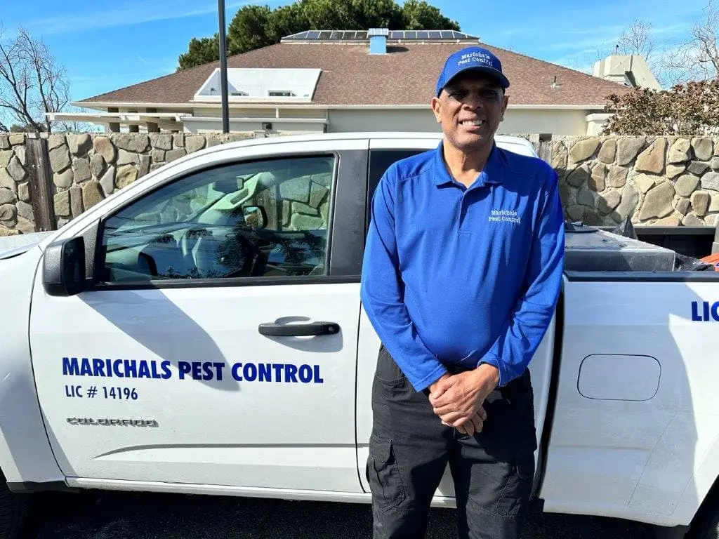 Marichal posing next to his pest control truck, prepared for pest management services.